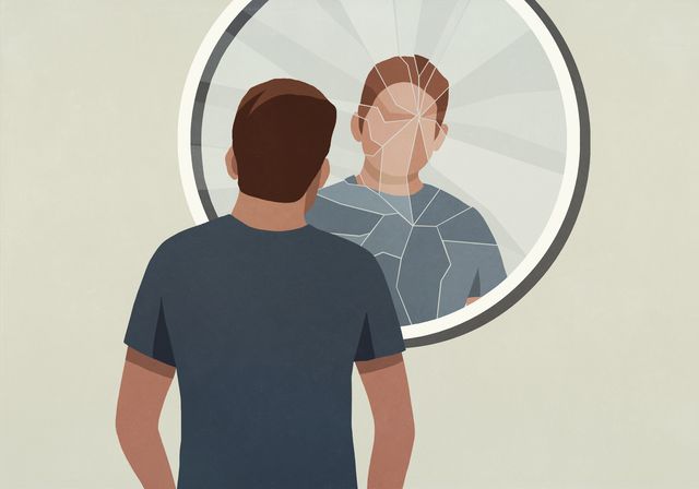 young man looking into cracked mirror