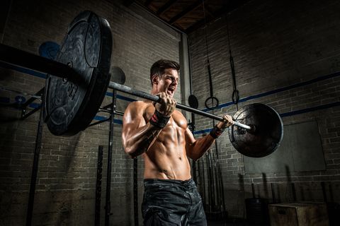 Young man performing bicep curls with barbell in gym