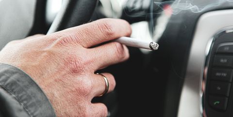young man smokes cigarette while driving