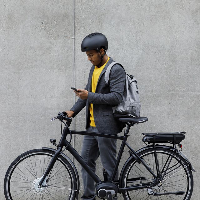 young man standing by electric bicycle using smartphone