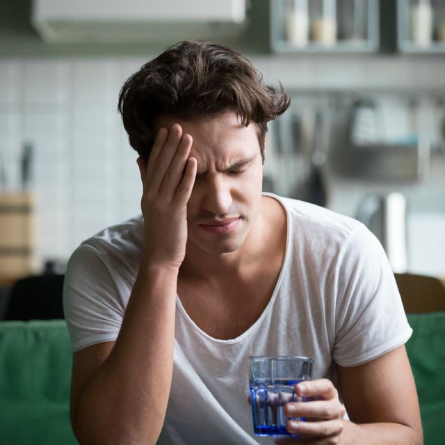 young man suffering from headache, migraine or hangover at home