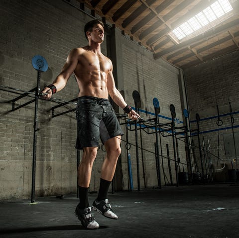 Young man using skipping rope in gym