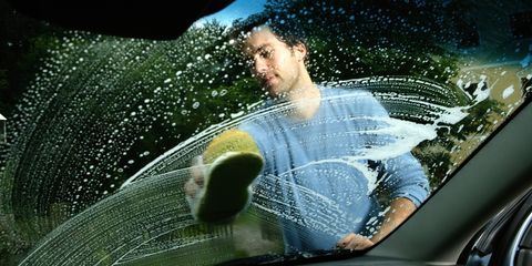 young man washing car, view through window