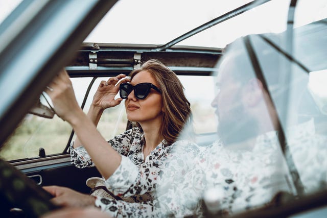 young married couple riding in vintage convertible car