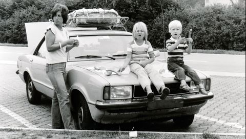 jonge moeder met twee kinderen op de motorkap in de jaren zeventig