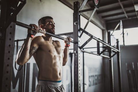 young muscular build athlete exercising pullups in a gym