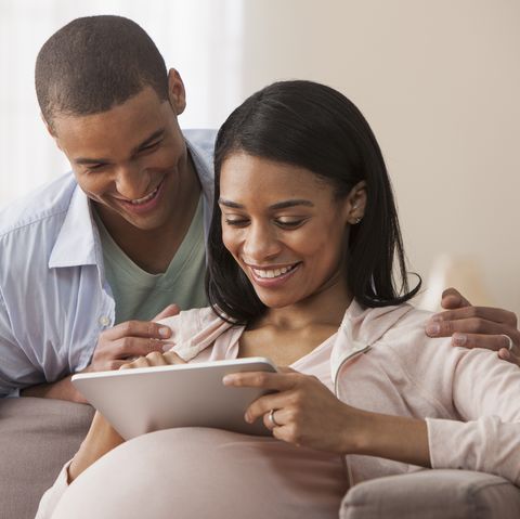 Young parents to be sitting with electronic tablet