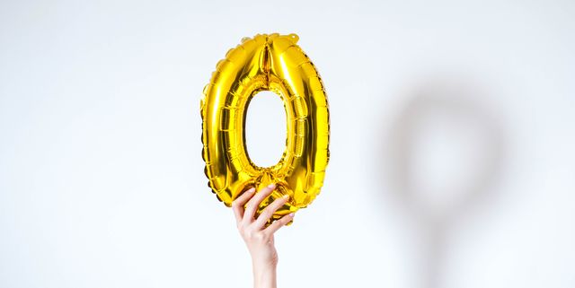 a young person is holding a golden colored number zero on a white background