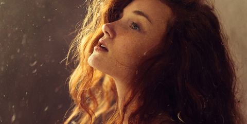Young redhead woman with feathers falling around