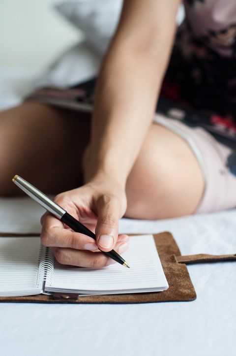 a young southeast asian woman is writing on her journal