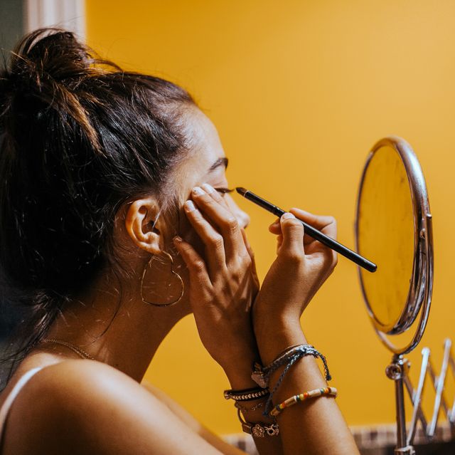 stockfoto van een vrouw die makeup aanbrengt voor een spiegel