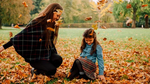 Young woman and little girl playing with autumn leaves on a meadow Young woman and little girl playing with autumn leaves on a meadow