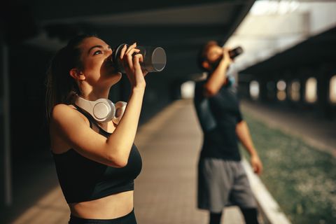 young woman and man drinking protein shake after workout