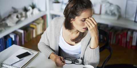 young woman at home at desk suffering headache