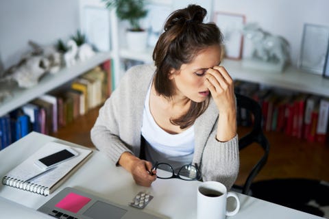 Young woman at home at desk suffering headache