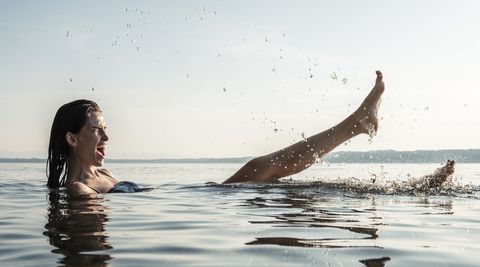 young woman bathing in lake starnberg, splashing with water, germany