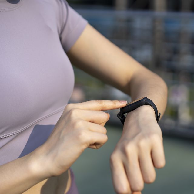 young woman checking the sports watch measuring heart rate and performance after running