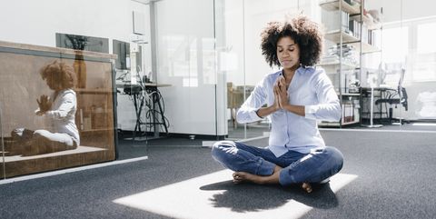Young woman doing yoga in office