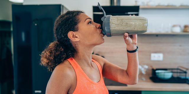 young woman drinking protein shake after workout at home