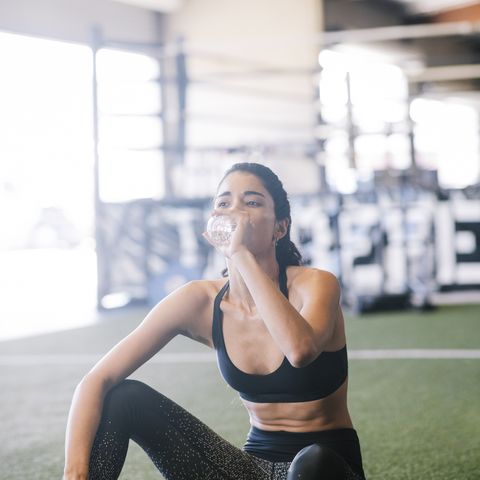 young woman drinks water at gym