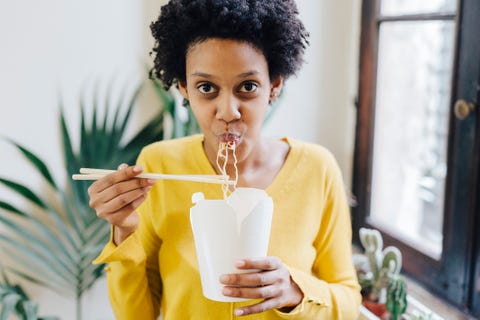 Young woman eating Asian noodles for lunch with chopsticks