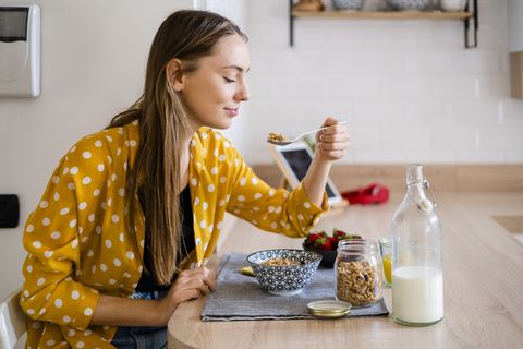 young woman enjoying breakfast in kitchen at home