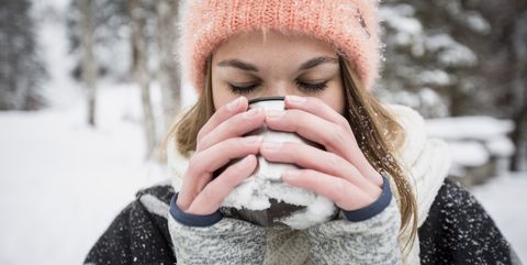 Young woman enjoying hot drink outdoors in winter
