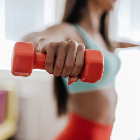 Young woman exercising with her weights in the living room