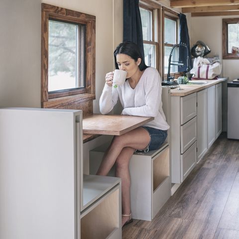 young woman having tea in her tiny house