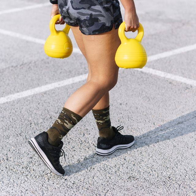 young woman holding kettlebells while walking on road