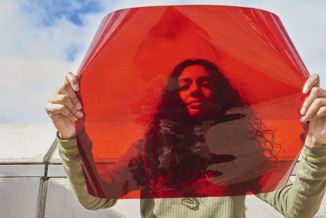young woman holding up red filter in front of face