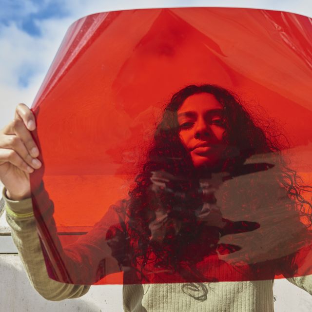 young woman holding up red filter in front of face