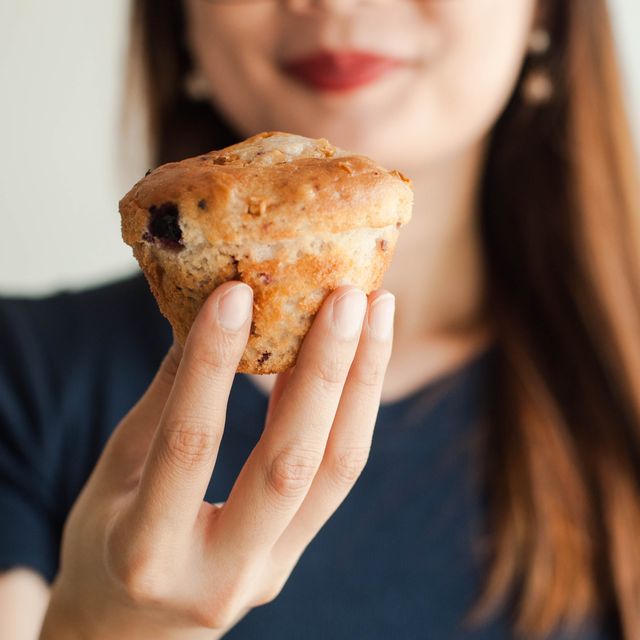 a young woman is eating a fruit muffin