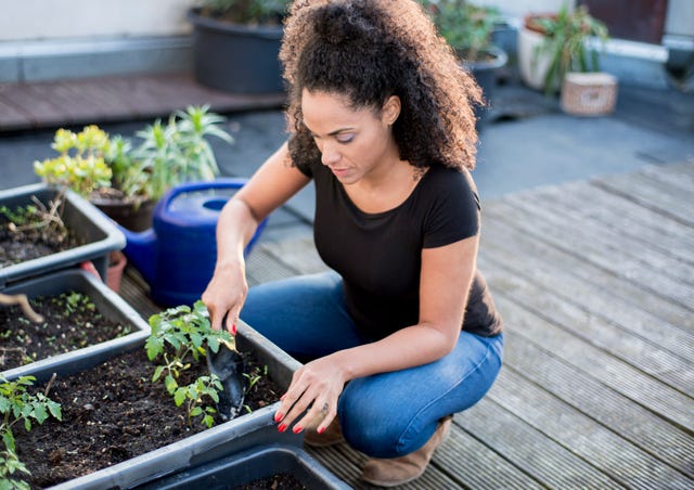 young woman is gardening on her urban rooftop