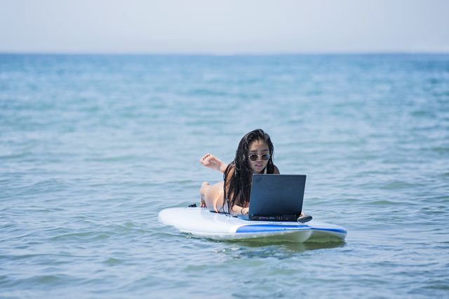 a young woman  is using  laptop on a surfboard