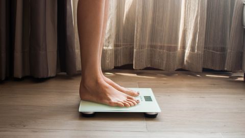 a young woman is weighing herself in a weighing scale