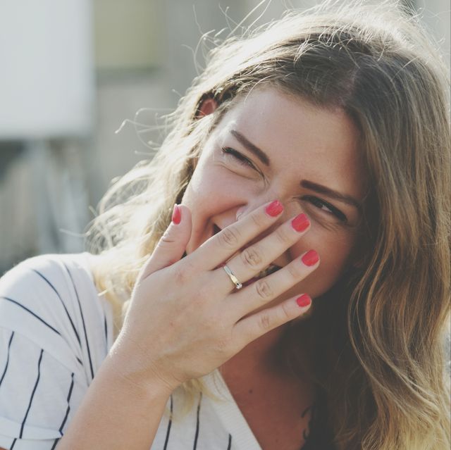 young woman laughing while hiding mouth with hand