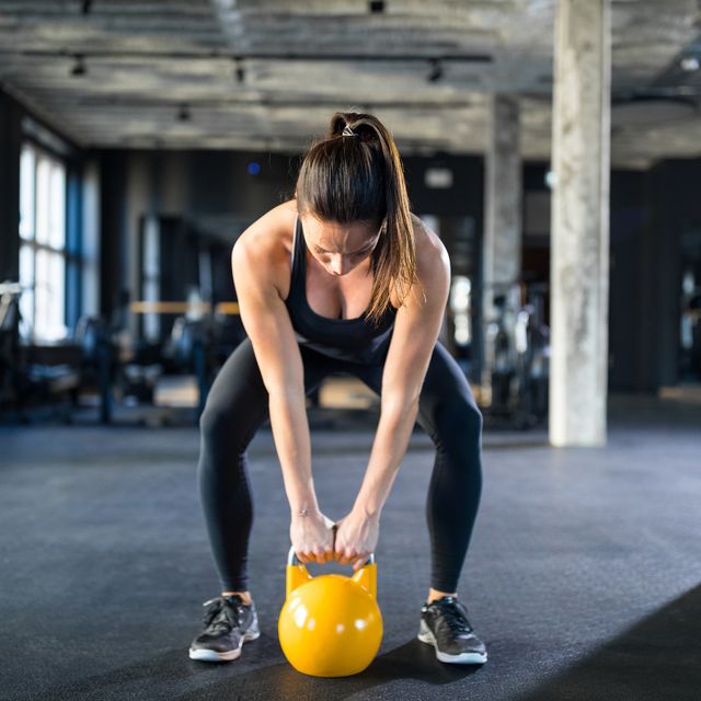 young woman lifting kettlebell in gym