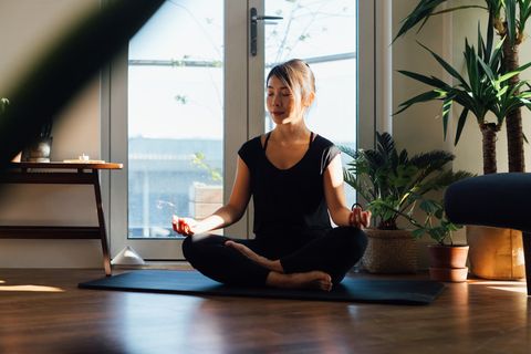 young woman meditating while sitting at home