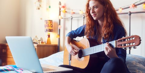 young woman on bed with guitar and laptop