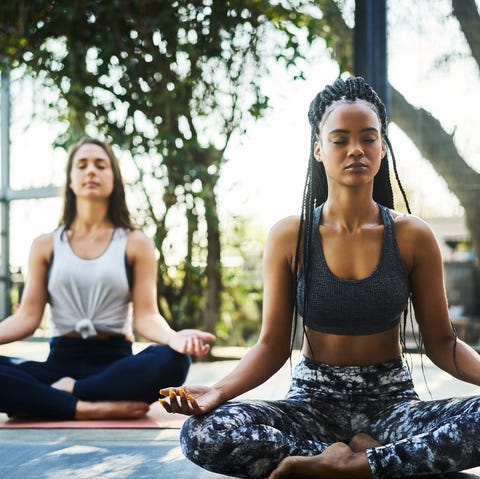 Young woman practicing lotus position with friend young woman practicing lotus position with friend