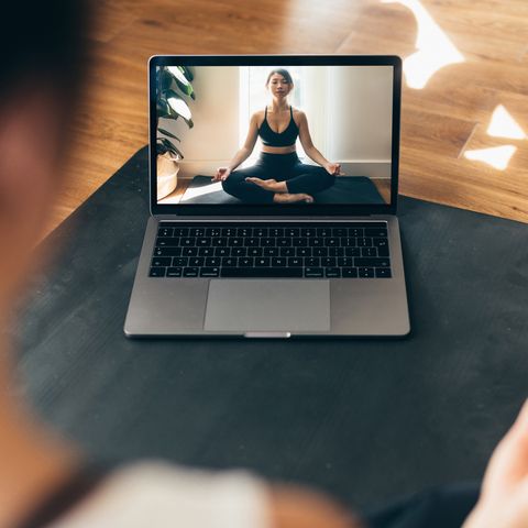 young woman practising yoga and meditation with a video lesson on laptop