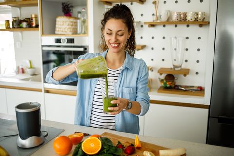 Young woman preparing a green smoothie at home