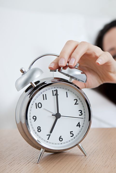 young woman reaching for alarm clock