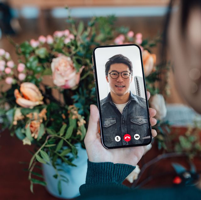 young woman receiving flower bouquet while having a video call with her love