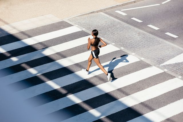 young woman running on zebra crossing