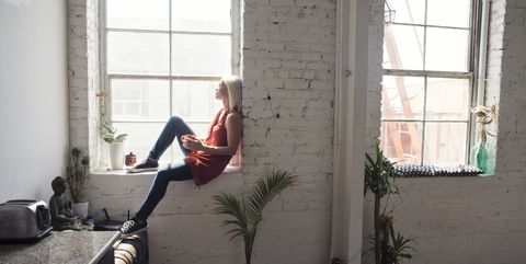 Young woman sitting on windowsill in a loft