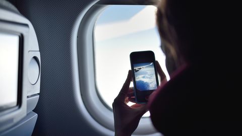 jonge vrouw neemt foto van vleugel in vliegtuig