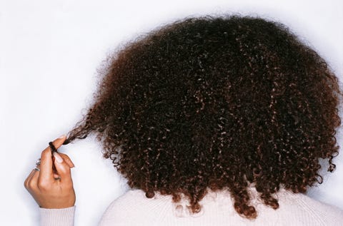 young woman twisting hair round finger, rear view