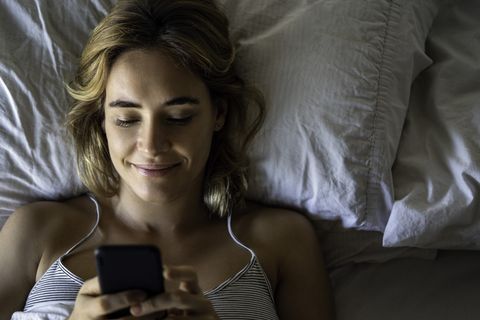 young woman using smartphone on bed